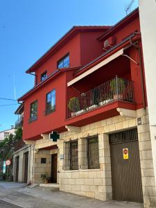 a red building with a balcony on a street at Casa de los boticarios, casa rural in El Arenal