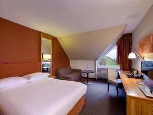 um quarto de hotel com uma cama grande e uma escrivaninha em Mövenpick Hotel Egerkingen em Egerkingen