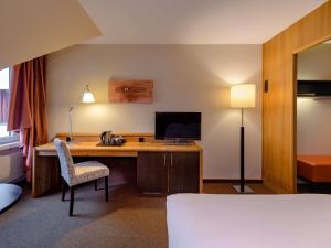 um quarto de hotel com uma secretária e uma televisão em Mövenpick Hotel Egerkingen em Egerkingen