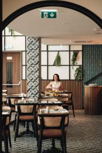 a woman sitting at a table in a restaurant at Leonardo Boutique Hotel Larnaca in Larnaca