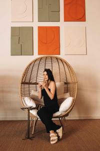 a woman is sitting in a rattan chair at Leonardo Boutique Hotel Larnaca in Larnaca