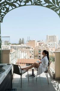 a woman sitting in a chair on a balcony at Leonardo Boutique Hotel Larnaca in Larnaca