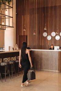 a woman walking through a restaurant with a purse at Leonardo Boutique Hotel Larnaca in Larnaca