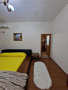 a bedroom with a yellow bed and a rug at The Koplik Guesthouse in Koplik