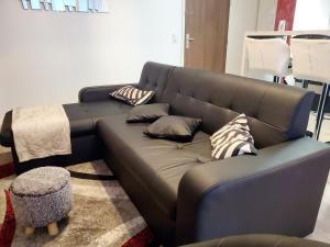 - un canapé brun dans le salon avec des oreillers dans l'établissement Le Petit Versailles, à Franconville