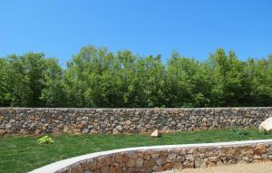 a stone wall with grass and trees behind it at Beautiful Home In Sveti Anton With Wifi in Sveti Anton