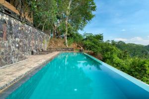 a blue swimming pool next to a stone wall at Cinnamon Museum Mirissa in Mirissa