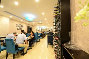 pessoas sentadas em mesas em um restaurante com prateleiras de vinho em Hanoi Emerald Waters Hotel & Spa em Hanói