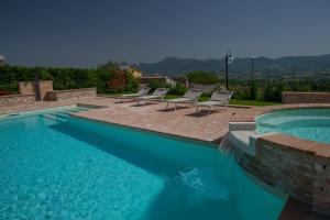 une piscine avec des chaises longues et une piscine dans l'établissement Il Casato, à Castelraimondo