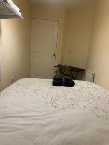 a white bed with a bag sitting on top of it at Little flat at the top in West Bromwich