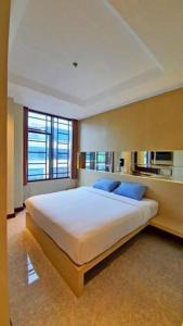 una camera da letto con un grande letto bianco con cuscini blu di MP Hotel Kelapa Gading a Giacarta