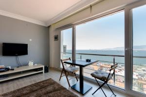 - un salon avec une table, des chaises et une grande fenêtre dans l'établissement Windows On The Bay - izmir, à Konak