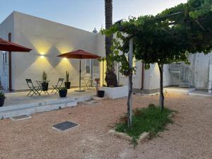 a house with a patio with a table and umbrella at Stagnone Sunset Holidays in Marsala