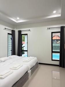 a white bedroom with a large bed and two windows at นงนุช วิลเลจ&พลูวิลล่า in Ban Nong Bua +26 photos