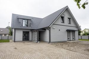 een groot wit huis met een schilddak bij Sun Side Apartments Pärnu in Pärnu