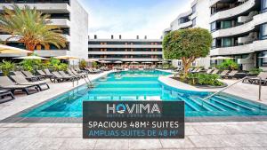 a swimming pool with lounge chairs and a hotel at HOVIMA Suites Costa Adeje in Adeje
