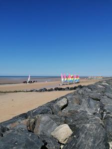 a beach with a group of umbrellas on the beach at Charmante maison près de la mer in Asnelles