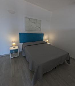 a bedroom with a bed with a blue headboard and two lamps at B&b Ranieri in Le Castella