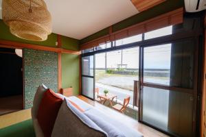 a room with a bed and a window with a view of the ocean at 南知多山海ビーチフロント左衛門亭 in Minamichita