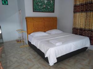 a bedroom with a large bed with white sheets and pillows at Hotel Tropicana in Tentena