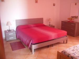 1 dormitorio con 1 cama roja y 2 mesitas de noche en Appartamento MareNatura, en Cardedu