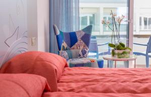 a bedroom with a bed and a chair and a table at Nicholas Color Hotel in Ayia Napa