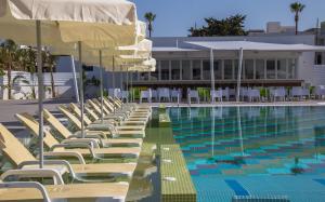 a pool with chairs and umbrellas next to a building at Nicholas Color Hotel in Ayia Napa