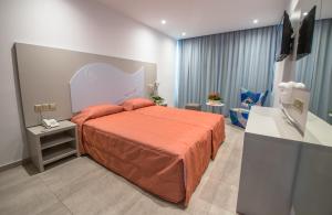 a bedroom with a bed with an orange bedspread at Nicholas Color Hotel in Ayia Napa