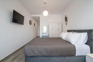 a bedroom with a bed and a flat screen tv at Kos Mare - Elegant Beachfront Stay in Paradeísi