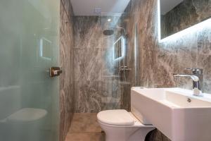 a bathroom with a toilet and a sink and a shower at Kos Mare - Elegant Beachfront Stay in Paradeísi