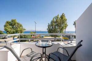 a balcony with a table and chairs and the ocean at Kos Mare - Elegant Beachfront Stay in Paradeísi