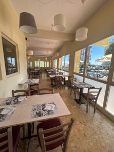 a restaurant with tables and chairs and windows at Hotel Ines in Cesenatico