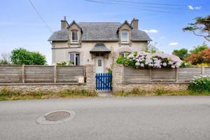 Una casa con una valla con flores. en Vue mer - Maison pour 8 avec jardin et terrasse, en Plouguerneau