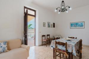 Una sala de estar con una mesa y sillas y una lámpara de araña. en Casa Damari-Fronte spiaggia, en Petrosino