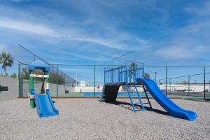 a playground with two slides in front of a fence at Wait 'n Sea Retreat Spacious Oceanfront Condo in Puerto Peñasco