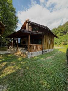 a small building with a porch on a grass field at UNA Dream in Ivišovo Greblje +8 photos