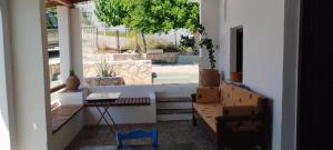 a porch with a bench and a table and a tree at Agrikia House fully renovated peaceful 1km from Plakias beach in Plakias