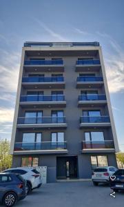 a tall building with cars parked in a parking lot at Blue Feelings Studio in Mamaia Nord