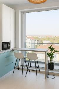 a kitchen with blue cabinets and two chairs and a large window at Blue Feelings Studio in Mamaia Nord +3 photos