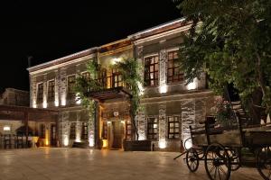 un viejo edificio de piedra con un carruaje delante de él por la noche en Elif Stone House, en Ürgüp