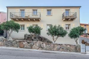 a building with two balconies and trees in front of it at Petra Maris Luxury Rooms in Santa Teresa Gallura
