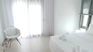 a bedroom with a bed and a chair and a window at Niovi Boutique Apartments in Afitos
