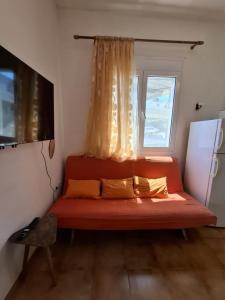 a red couch in a room with a window at Not quite a treehouse in Vrontados
