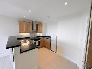 a kitchen with wooden cabinets and a white refrigerator at West Beach - Holiday Apartments in Westward Ho