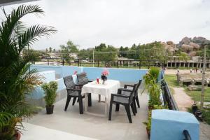 a patio with a table and chairs on a balcony at Ranjana Guesthouse in Hampi