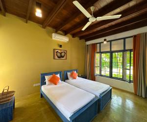 a bedroom with two beds and a ceiling fan at Gaia Lake Bungalow Kandalama in Dambulla