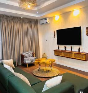 a living room with a green couch and a flat screen tv at Nook & Cranny apartment jahi in Mama