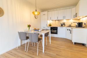 eine Küche mit einem weißen Tisch und Stühlen in der Unterkunft Matanzas- Penthouse mit Dachterrasse, Sauna & strandnah! in Kellenhusen