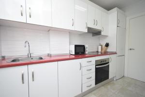 a white kitchen with a sink and a microwave at ALLONAYA - Fincas Arena in Benidorm