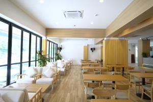 a restaurant with white chairs and tables and windows at Kokotel Rayong Beachfront in Ban Pak Khlong Phe